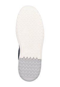 Sulan på en sko med vit textur, zickzackmönster och triangulära accenter. Den grå gummidelen övergår till en slät vit design.