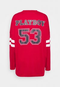 Rotes Langarm-T-Shirt mit weißen gestreiften Akzenten an den Ärmeln, mit "PLAYBOY" und "53" in Schwarz auf der Rückseite bedruckt. Aus Baumwollmischung.
