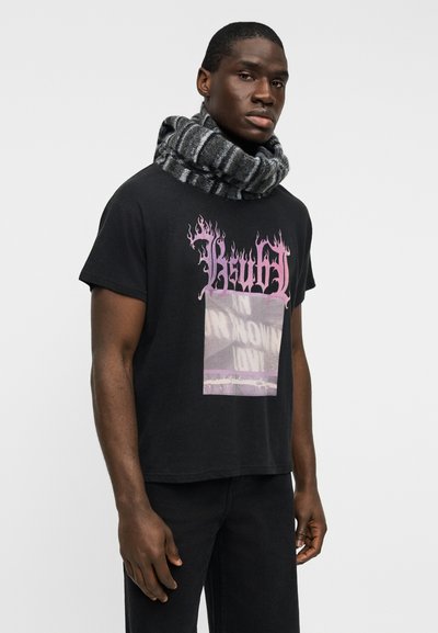 Μαύρο κοντομάνικο μπλουζάκι με ροζ φλόγα και ημιδιαφανές σχέδιο. Συνδυάζεται με μαύρο και γκρι ριγέ πλεκτό κασκόλ.