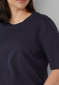 Navyblaue Baumwoll-T-Shirt mit rundem Ausschnitt und kurzen Ärmeln. Der Stoff wirkt weich mit einer glatten Textur und minimalen Design-Details.