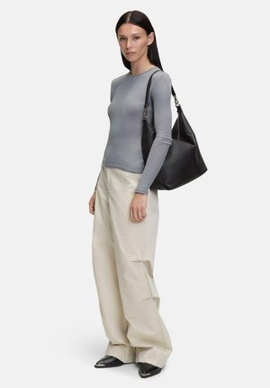 Haut à manches longues gris côtelé associé à un pantalon large crème, un sac à bandoulière en cuir noir et des chaussures à bouts pointus noires. Design minimaliste.
