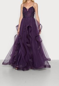 Fioletowa wieczorowa suknia z dopasowanym gorsetem ozdobionym koralikami, cienkimi ramiączkami oraz zwiewną, warstwową spódnicą z tiulu z falbaniastymi brzegami.