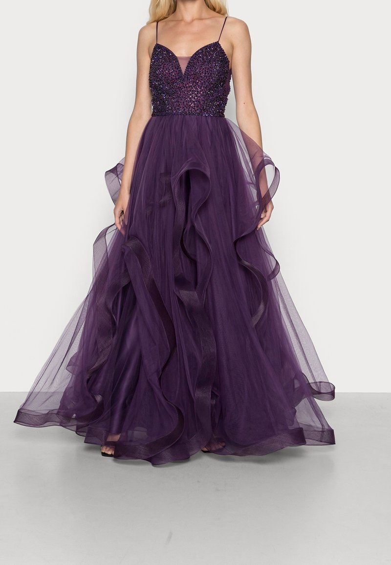 Fioletowa wieczorowa suknia z dopasowanym gorsetem ozdobionym koralikami, cienkimi ramiączkami oraz zwiewną, warstwową spódnicą z tiulu z falbaniastymi brzegami.