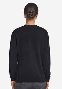 Czarny sweter z miękkiego materiału, charakteryzujący się prostym krojem, długimi rękawami i okrągłym dekoltem. Prosty design bez wyraźnych detali.