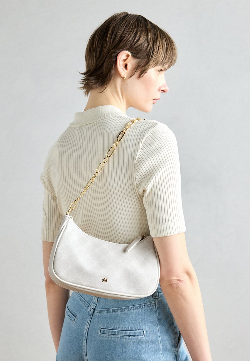 Sac à épaule blanc au design courbé, avec une bandoulière en chaîne dorée et un logo subtil. Texture lisse, avec un extérieur à motifs.