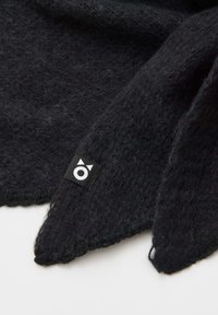 Zwart wollen sjaal met een zachte textuur, met scherpe randen en een klein label met een wit grafisch ontwerp aan één kant.