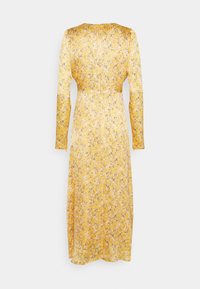 Gul blommig klänning med långa ärmar, plisserad struktur och midjehögt skärp. Mönstret har små svarta och vita detaljer utspridda.