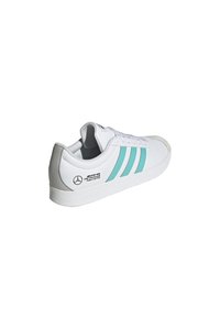 Vit sneaker med ljus teal-stripe, gummikänga och förstärkt tåfodring. Har logodetaljer på utsidan och hälen.