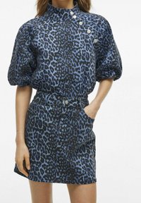 Denimklänning i blå och svart leopardmönster, hög krage, puffärmar och dekorativa knappar på axeln.