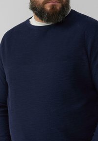 Dunkelblauer Pullover mit einem strukturierten Rippmuster über der Brust. Verfügt über einen Rundhalsausschnitt und lange Ärmel. Weicher Stoff.