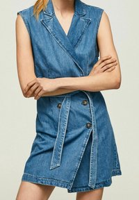 Denimmekko, jossa on hihaton malli, kauluspanta, tuplapainikkeet ja itsesidottava vyö. Sininen väri, jossa on hieman teksturoitu pinta.