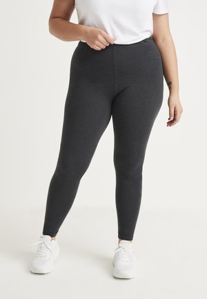 Rekbare grijze leggings met een elastische tailleband, met een gladde textuur en een aansluitend ontwerp, gecombineerd met witte sportschoenen.