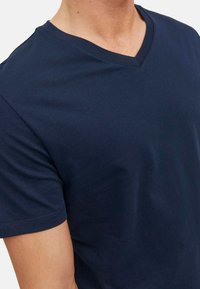 Granatowa koszulka typu v-neck wykonana z bawełny, z krótkimi rękawami i gładką fakturą, bez widocznych wzorów czy akcentów.