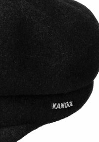 Zwarte vilten hoed met een ronde bovenkant en een zachte rand. Bevat een geborduurd "Kangol"-logo aan de zijkant. Gelaagd materiaal.