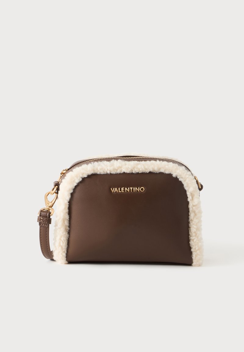 Καφέ τσάντα Valentino crossbody με χρυσό λογότυπο, λευκή επένδυση shearling, χρυσό φερμουάρ και ρυθμιζόμενο λουράκι σε απλό φόντο.