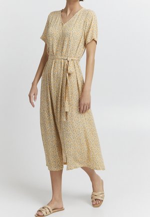 Robe florale jaune avec un décolleté en V, des manches courtes, une ceinture à la taille et une jupe fluide. Fabriquée en tissu léger avec une texture douce.