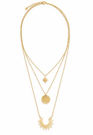 Collier en or à trois couches avec étoile, disque rond texturé et pendentifs en forme d'éclat de soleil sur des chaînes délicates.