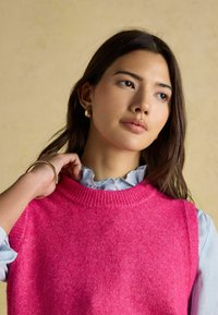 Roosa ilma varrukat särk ribatud kaelusega, mille peal on sinised triibulised särk, millel on ruffitud krae. Aktsentideks on kuldsed rõngaspärlid.