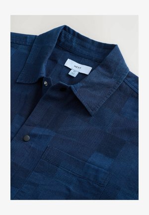 Camicia a maniche corte a quadri navy, realizzata in tessuto texture, con colletto button-down e una tasca sul petto.