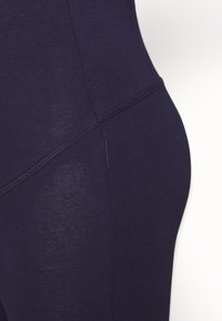 Navy workout leggings made of stretchy, smooth fabric with a fitted design; features flat seams and a high waistband for comfort.