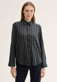 Black and white striped button-up shirt with long sleeves, a collar, and button details. The fabric has a soft, smooth texture.
