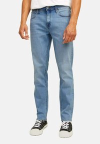 Jeans in denim azzurro chiaro con design a gamba dritta, stile a cinque tasche e chiusura classica con bottone e zip. Indossati con sneakers nere.