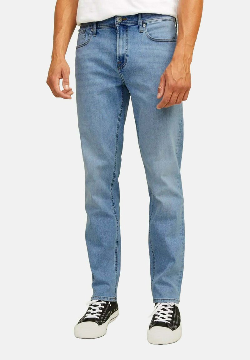 Jeans in denim azzurro chiaro con design a gamba dritta, stile a cinque tasche e chiusura classica con bottone e zip. Indossati con sneakers nere.