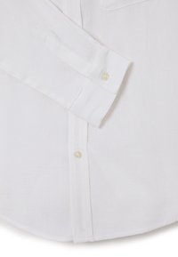 Camicia bianca in lino con colletto appuntito, maniche lunghe, polsini abbottonati e taschino frontale. La texture sembra leggera e leggermente stropicciata.