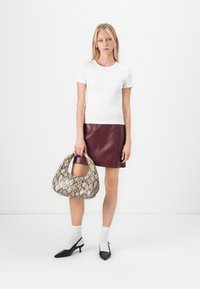 Hvit ribbet t-skjorte, burgunder lær skjørt, oversized slangeskinn veske, svarte slingback hæler, ankel-lange hvite sokker. Minimal bakgrunn.