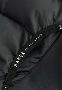 Czarna kurtka puchowa od wewnątrz z gładkim materiałem i subtelnym połyskiem. Posiada metkę z logo z napisem "BAKER by TED BAKER."