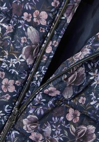 Marineblaue Steppjacke mit floralem Druck in verschiedenen Lila- und Rosatönen, ausgestattet mit einem silbernen Reißverschluss und gestepptem Muster.