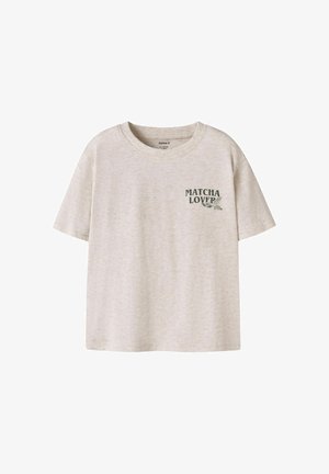 Beżowy t-shirt z krótkim rękawem i okrągłym dekoltem, z ciemnozielonym napisem „MATCHA LOVER” i grafiką liścia na lewej piersi.