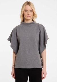 Grijze gebreide top met een hoge halslijn, brede flared mouwen en verticale gestructureerde strepen met subtiele metallic accenten. Te combineren met donkere broeken.