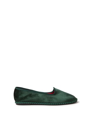 Zapato plano de terciopelo verde oscuro con punta redondeada, detalle de suela cosida y diseño de perfil bajo sobre fondo blanco.