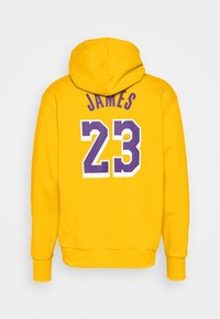 Sweat à capuche jaune avec lettrage violet. Au dos, "JAMES" et le numéro "23" imprimés en couleurs contrastées et en gras. Tissu doux et texturé.
