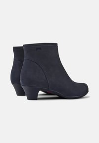Stivaletti blu navy realizzati in materiale morbido simile alla pelle scamosciata, con un tacco corto e una punta arrotondata, arricchiti da dettagli laterali discreti.