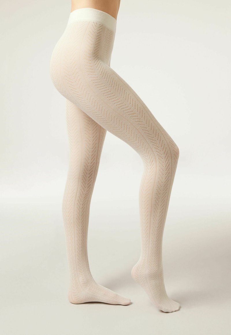 Collants crème à motif avec un design en zigzag texturé, présentant une taille large douce et une finition lisse.