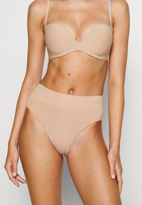 Hautfarbener BH aus Bio-Baumwolle mit vorgeformten Cups und nahtlosem Design, kombiniert mit hochgeschnittenen, hautfarbenen Slips mit einem glatten Bund.