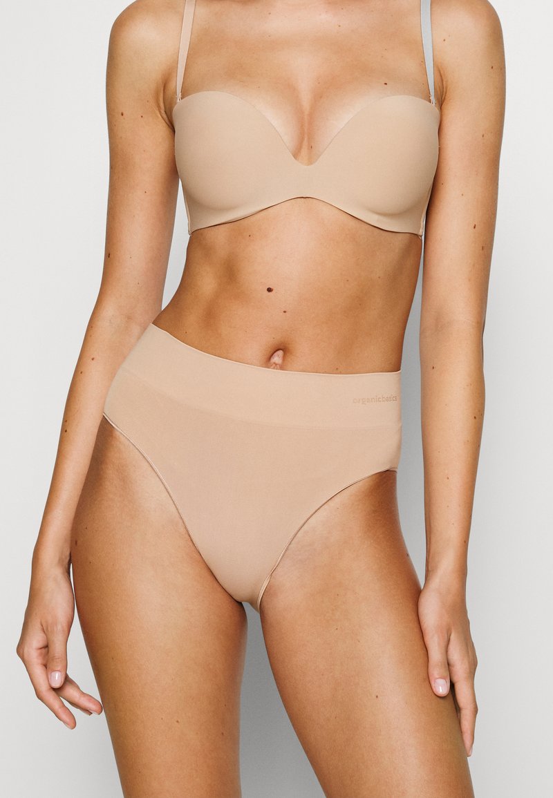 Hautfarbener BH aus Bio-Baumwolle mit vorgeformten Cups und nahtlosem Design, kombiniert mit hochgeschnittenen, hautfarbenen Slips mit einem glatten Bund.