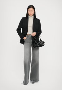 Black blazer, striped turtleneck, grey wide-leg jeans, and a black handbag with hardware details. Smooth textures and tailored fit.