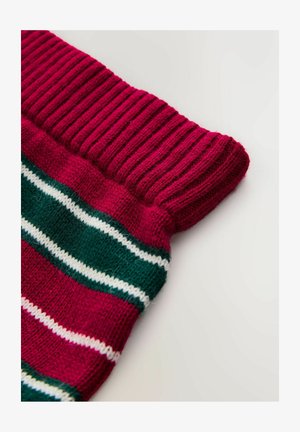 Nærbillede af en rød strikket manchet med grønne og hvide vandrette striber på en foldet sweaterærme.