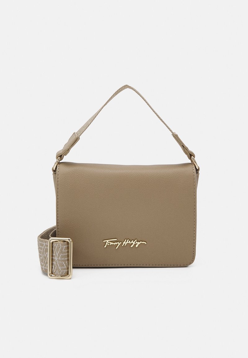 Sac à bandoulière en cuir beige avec sangle en tissu ajustable et logo signature doré sur le rabat avant.