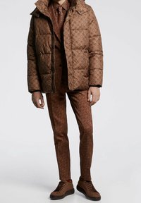 Brown puffer jacket with a hood and patterned texture, paired with a matching suit and sneakers. The suit features a geometric design.