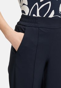 Granatowe spodnie sportowe z elastyczną talią, z boczną kieszenią oraz gładkim, lekkim materiałem, zapewniającym komfort i swobodę ruchu.