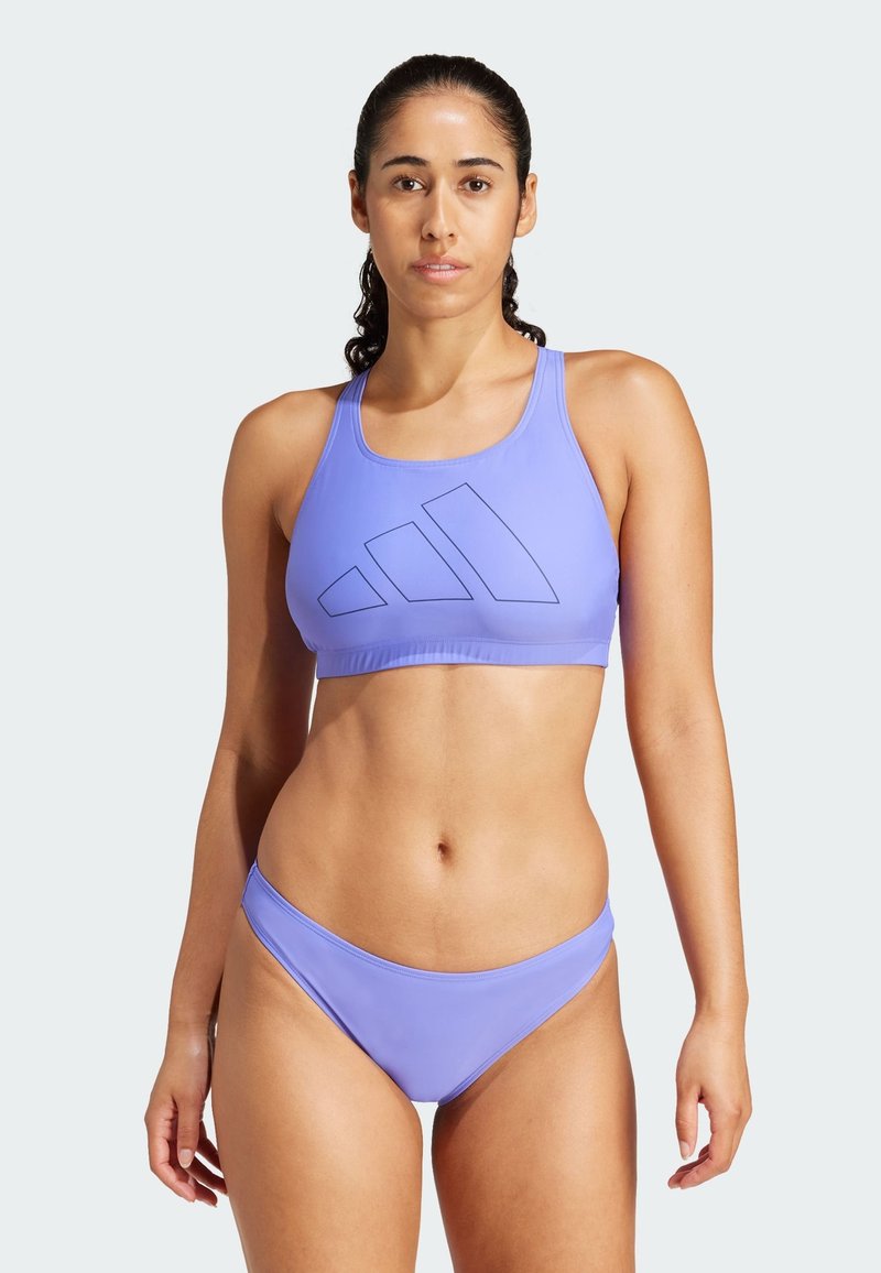 Ljubičasti atletski bikini set koji se sastoji od kratke majice s ugraviranim logotipom i niskim gaćicama koje se uklapaju. Glatka tkanina s minimalnim šavovima.
