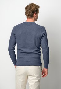 Pull en tricot bleu marine pour homme, avec un col rond, des manches longues et des poignets côtelés, conçu avec un tissu texturé.