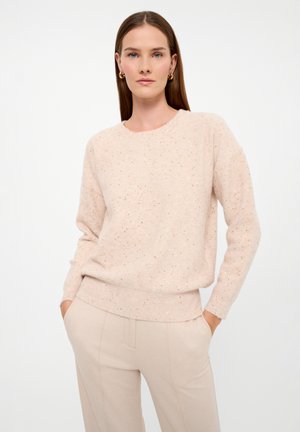 Maglione rosa chiaro con collo rotondo, maniche lunghe e orlo a coste. Presenta sottili macchie distribuite su tutto il tessuto. Texture morbida.