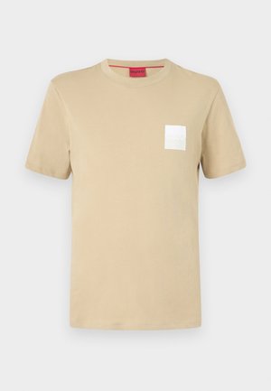 Beige cotton t-shirt with short sleeves, round neckline, and white square logo on the left chest. Smooth texture, casual design.