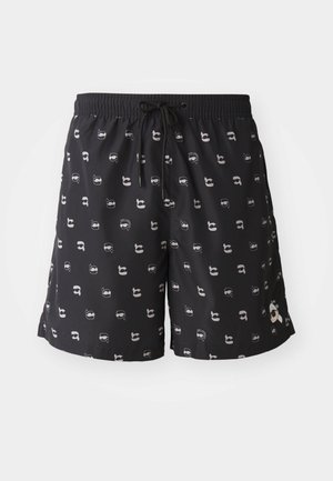 Črne kopalne hlače z elastičnim pasom in vrvico, ki imajo ponovljen vzorec svetlih karikaturastih obrazov.