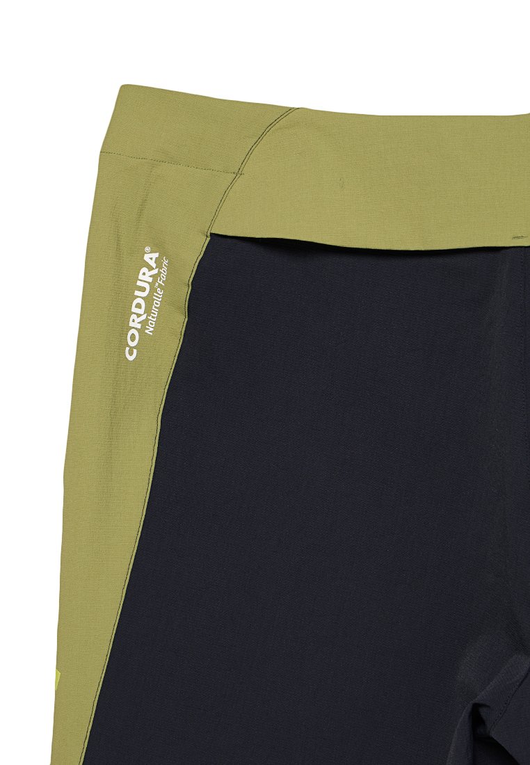 Nahaufnahme eines grünen und schwarzen Stoffpaneels mit dem Logo "CORDURA® Natural Fabric", das auf dem grünen Abschnitt gedruckt ist.